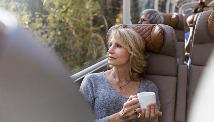 woman holds coffee mug and gazes out window onboard the rocky mountaineer